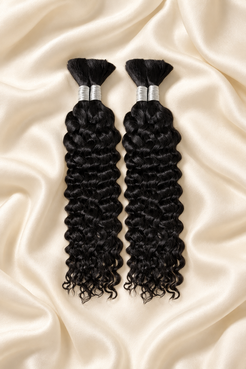 Two natural black water wave human hair bundles for boho braids displayed on ivory silk