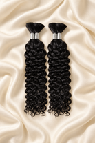 Two natural black water wave human hair bundles for boho braids displayed on ivory silk