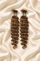 Two #27 honey blonde deep wave human hair bundles for boho braids displayed on ivory silk