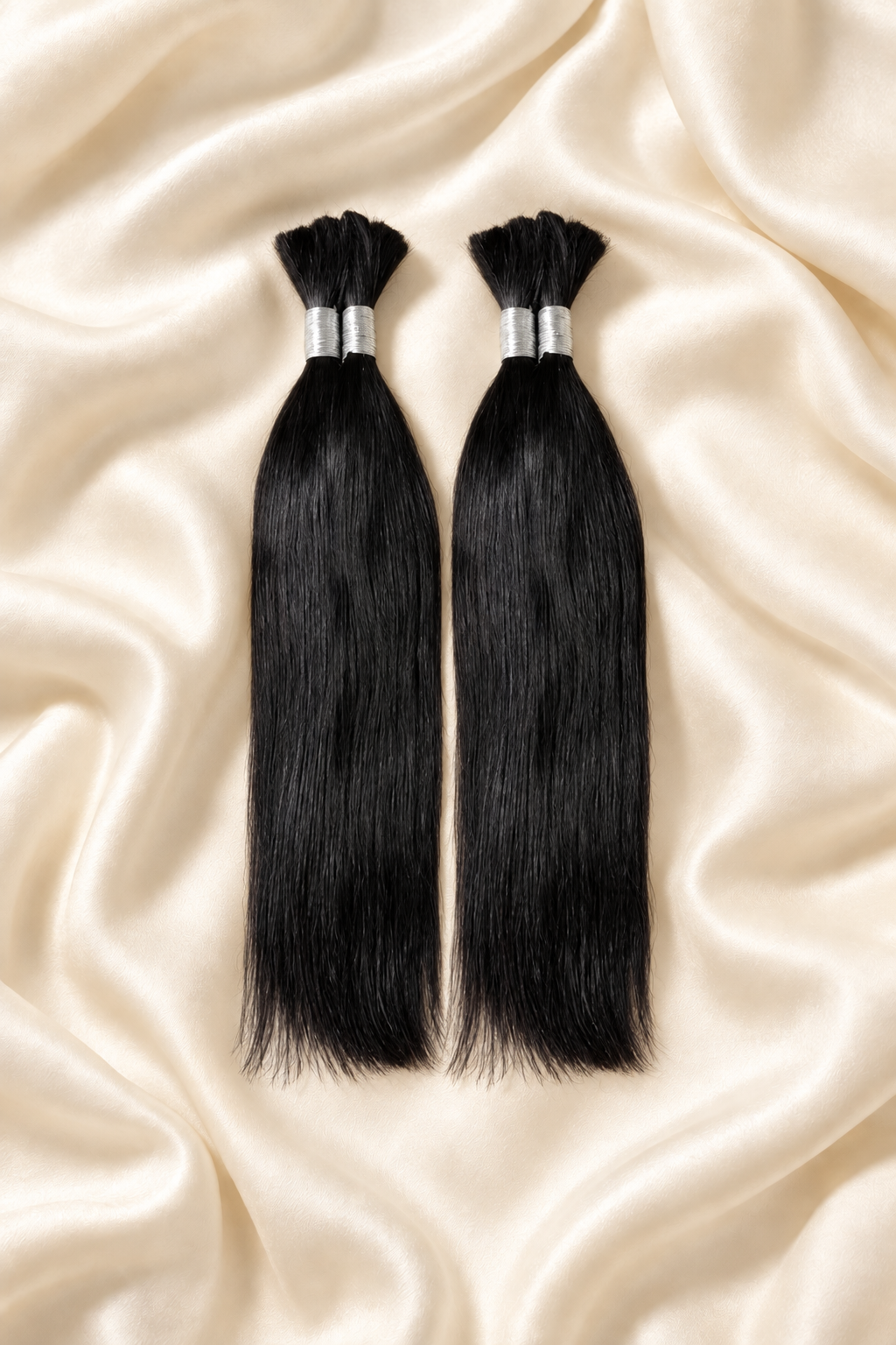 Two natural black straight human hair bundles for boho braids displayed on ivory silk