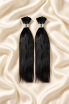 Two natural black straight human hair bundles for boho braids displayed on ivory silk