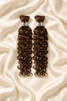 Two #30 auburn water wave human hair bundles for boho braids displayed on ivory silk