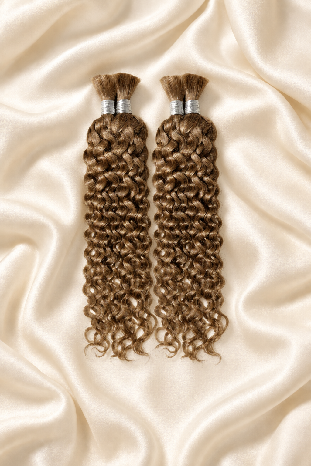 Two #27 honey blonde water wave human hair bundles for boho braids displayed on ivory silk