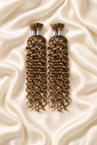 Two #27 honey blonde water wave human hair bundles for boho braids displayed on ivory silk