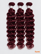 Three 99J burgundy deep wave human hair bundles with silver wraps on a pale gray background.